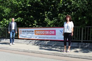 Der Lebacher Bürgermeister Klauspeter Brill und Claudia Köhler, Leiterin des Sachgebiets für Jugend, Frauen und Senioren präsentieren den Hinweisbanner auf das bundesweite Hilfetelefon. Foto: Kirsch/ Stadt Lebach